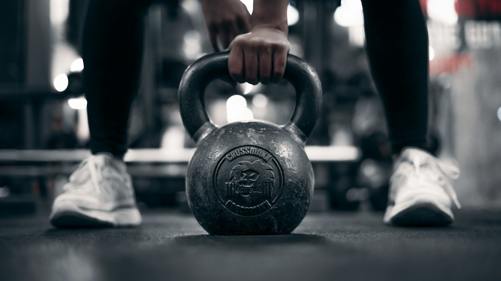 Mão a segurar um kettlebell no chão do ginásio