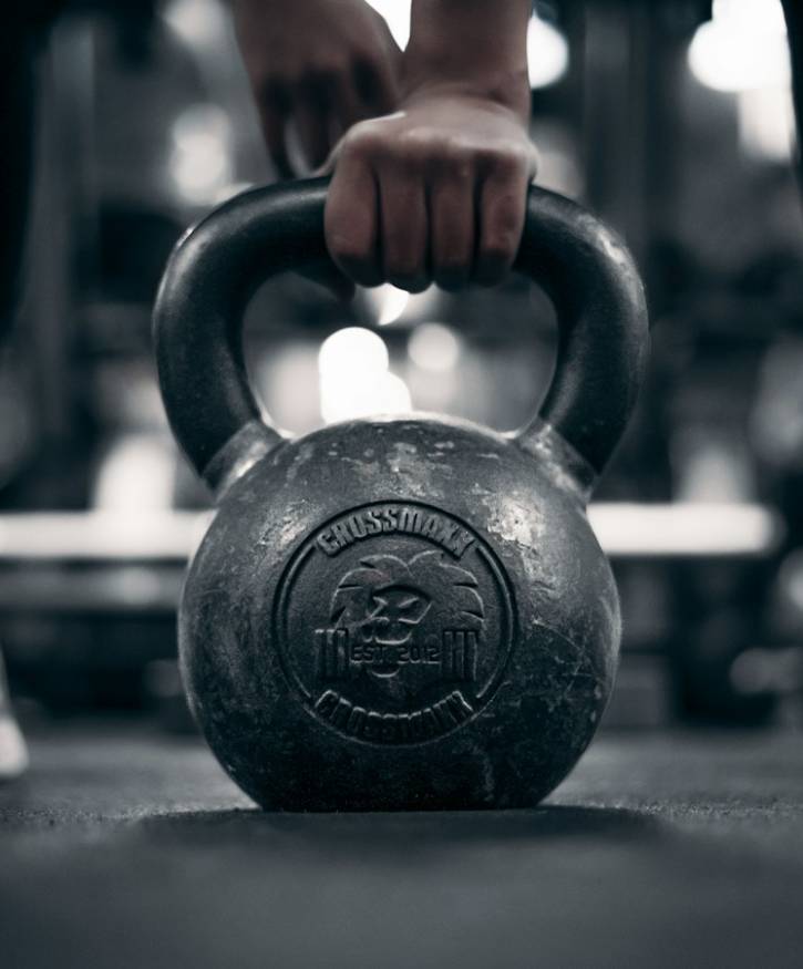 Mão a segurar um kettlebell no chão do ginásio